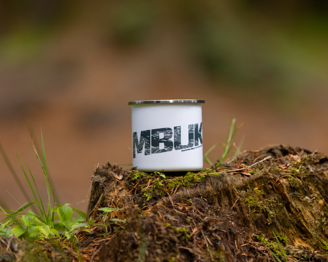 MBUK Enamel Mug on a log in the woods